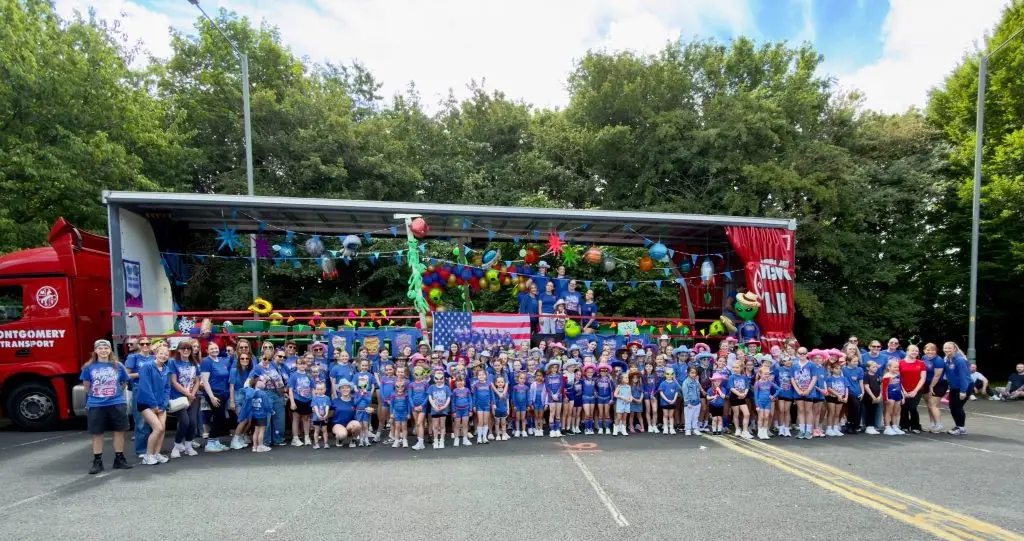 Infinity Cheer squad and coaches lined up in front of their Montgomery Transport-sponsored float before the carnival parade