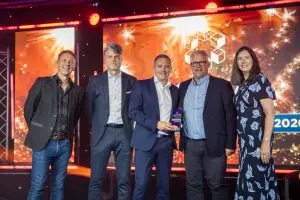 Award winner holding a UKWA Awards 2026 trophy on stage, joined by four others in front of a lit backdrop