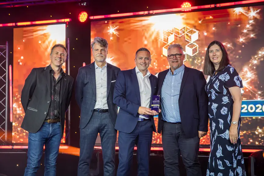 Award winner holding a UKWA Awards 2026 trophy on stage, joined by four others in front of a lit backdrop