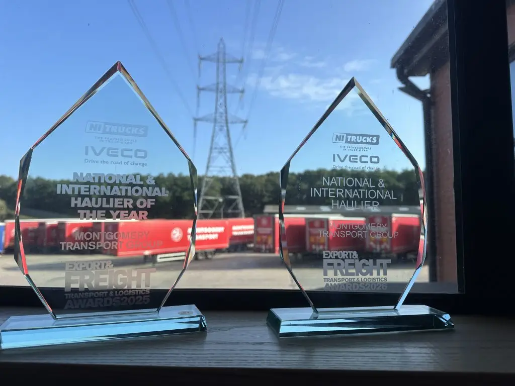 Export & Freight National & International Haulier trophies from 2025 and 2026, with red Montgomery trailers in the yard behind